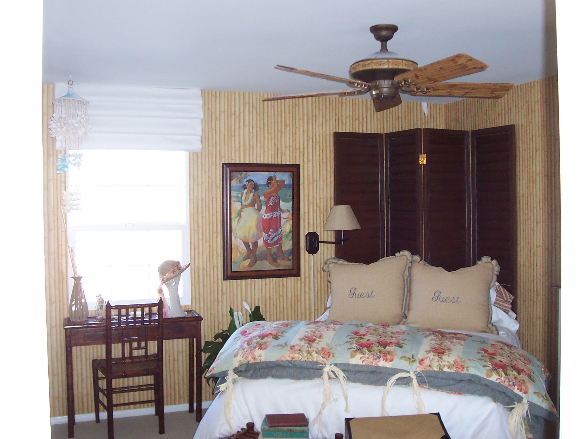 Guest bedroom with bamboo wall paneling, floral bedding, and tropical artwork