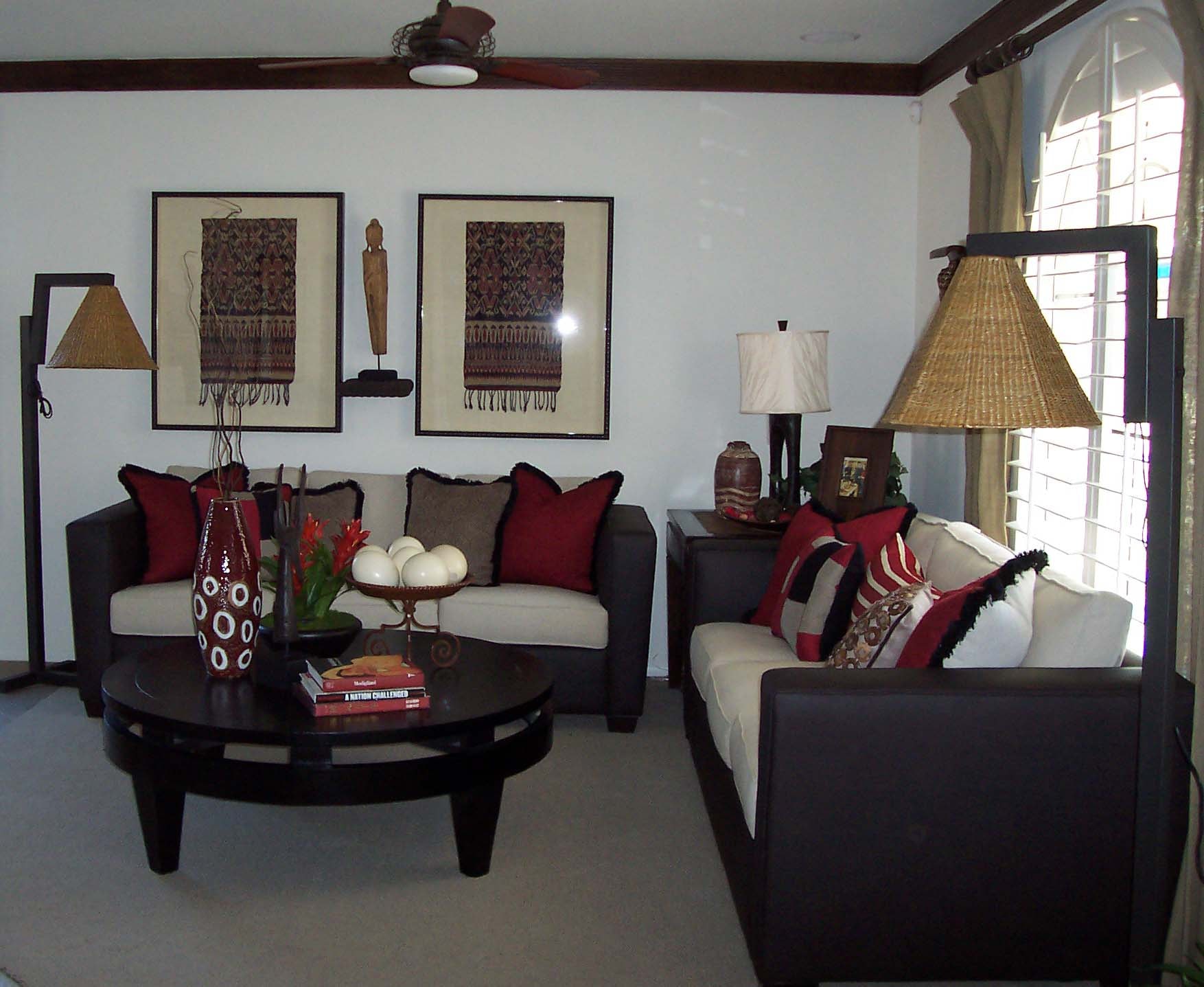 Living room with dark wood furniture, red accent pillows, and framed textile artwork