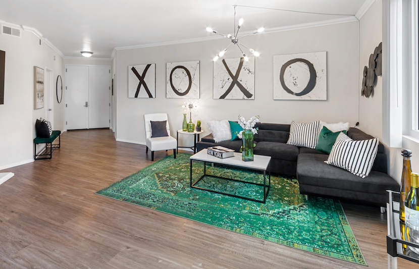 Living room with an emerald rug, dark sectional, and graphic artwork