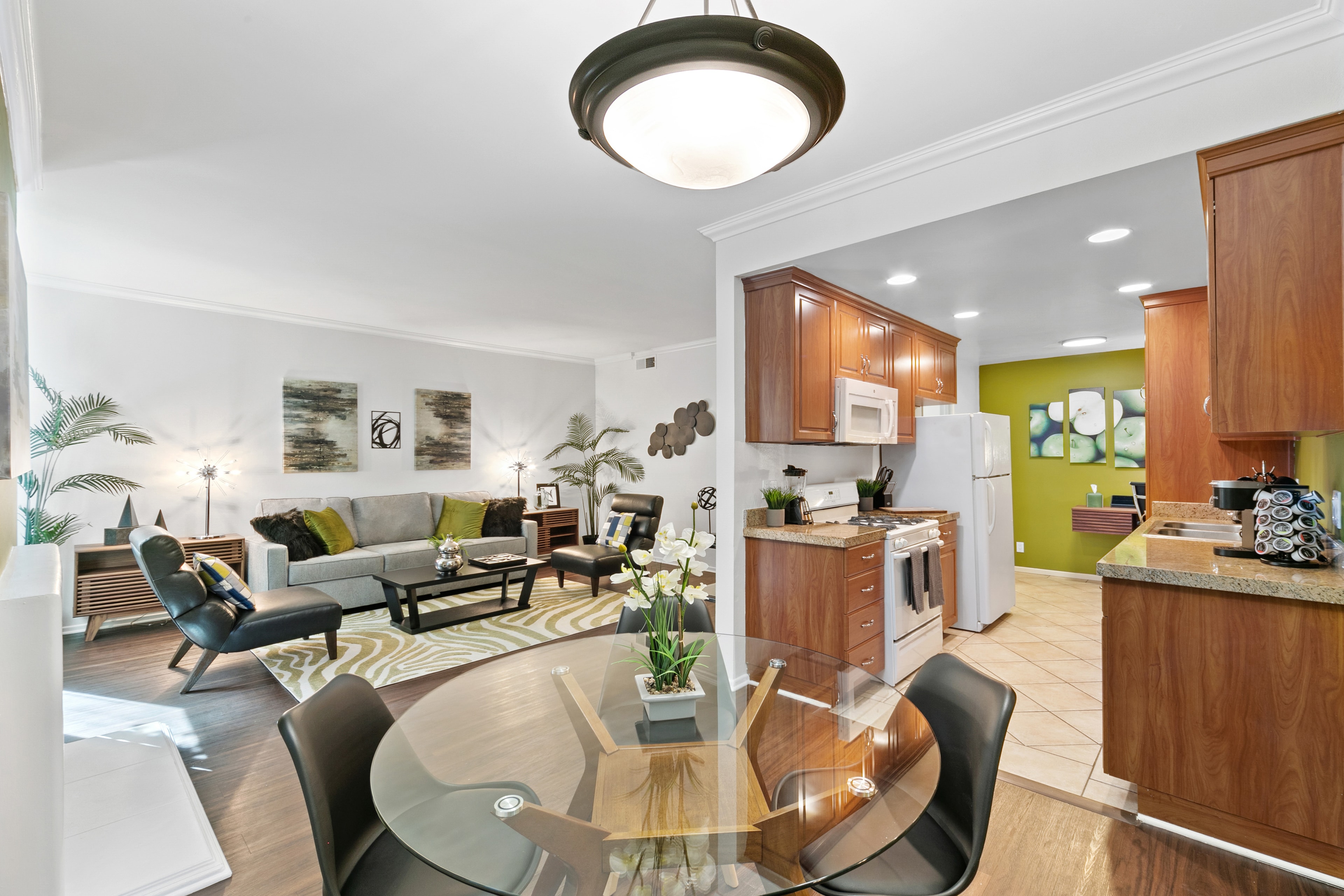 Open-plan kitchen and dining area with warm wood cabinetry and green accents