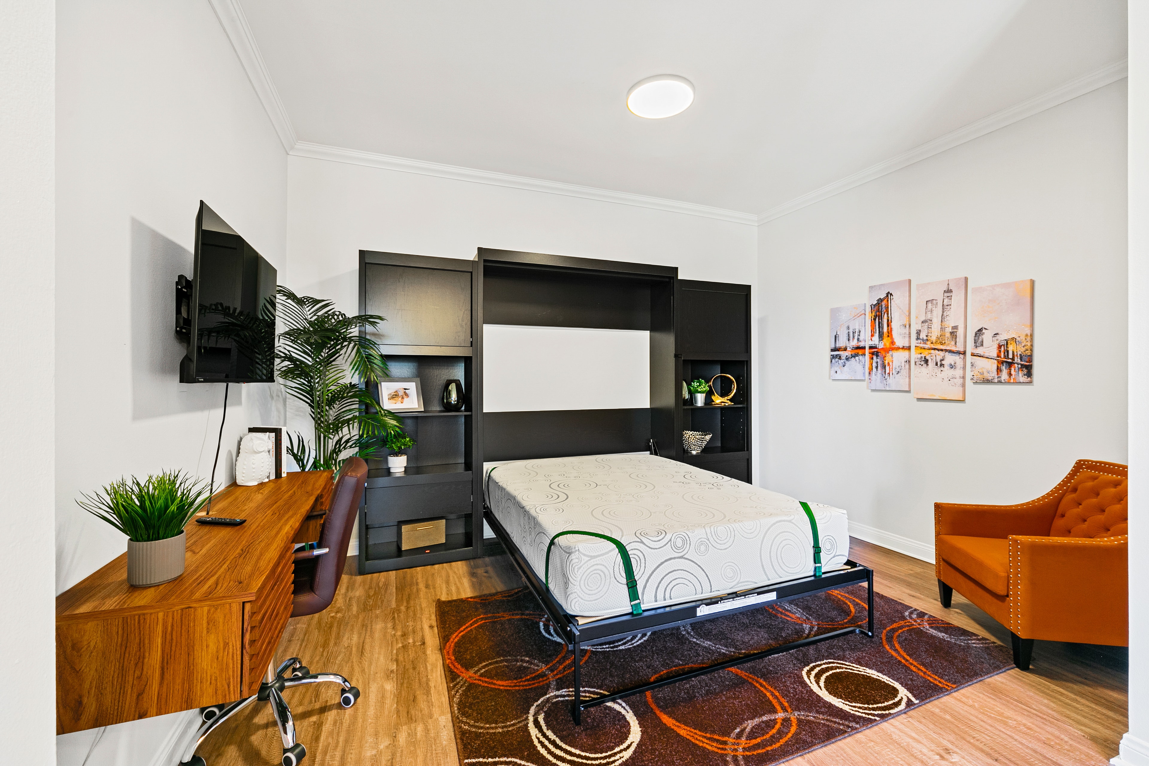 Modern den with dark built-ins, desk, and orange accent chair