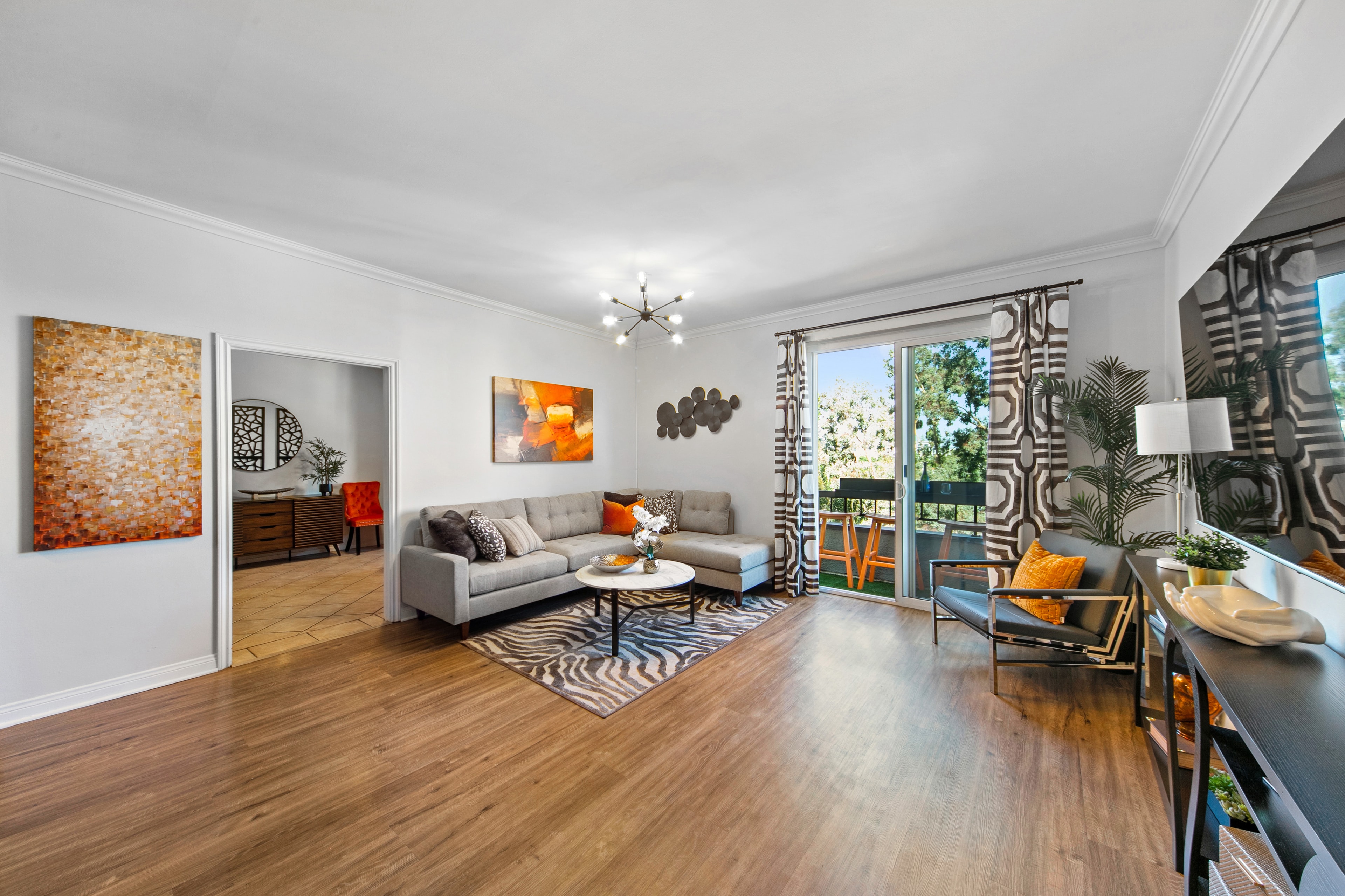 Living room with warm orange accents, patterned drapery, and contemporary seating