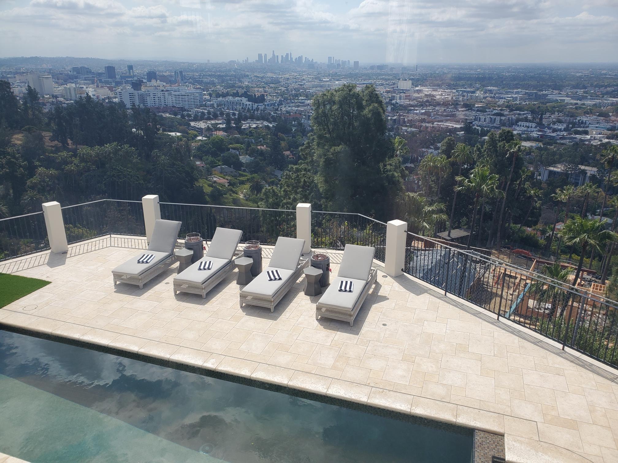 Pool terrace with lounge chairs and panoramic Los Angeles skyline view
