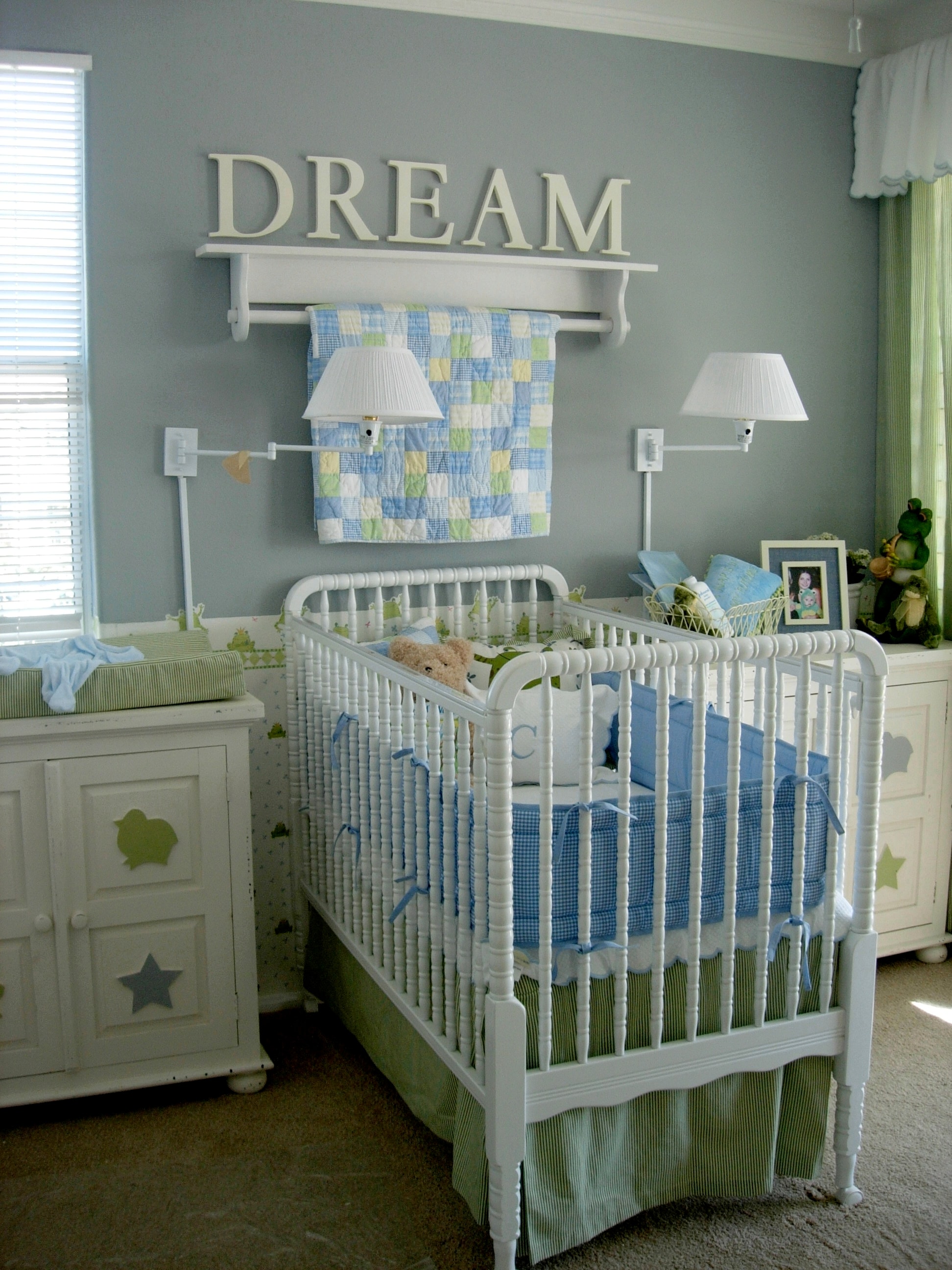 Soft blue and green nursery with white crib, patchwork bedding, and dream wall lettering