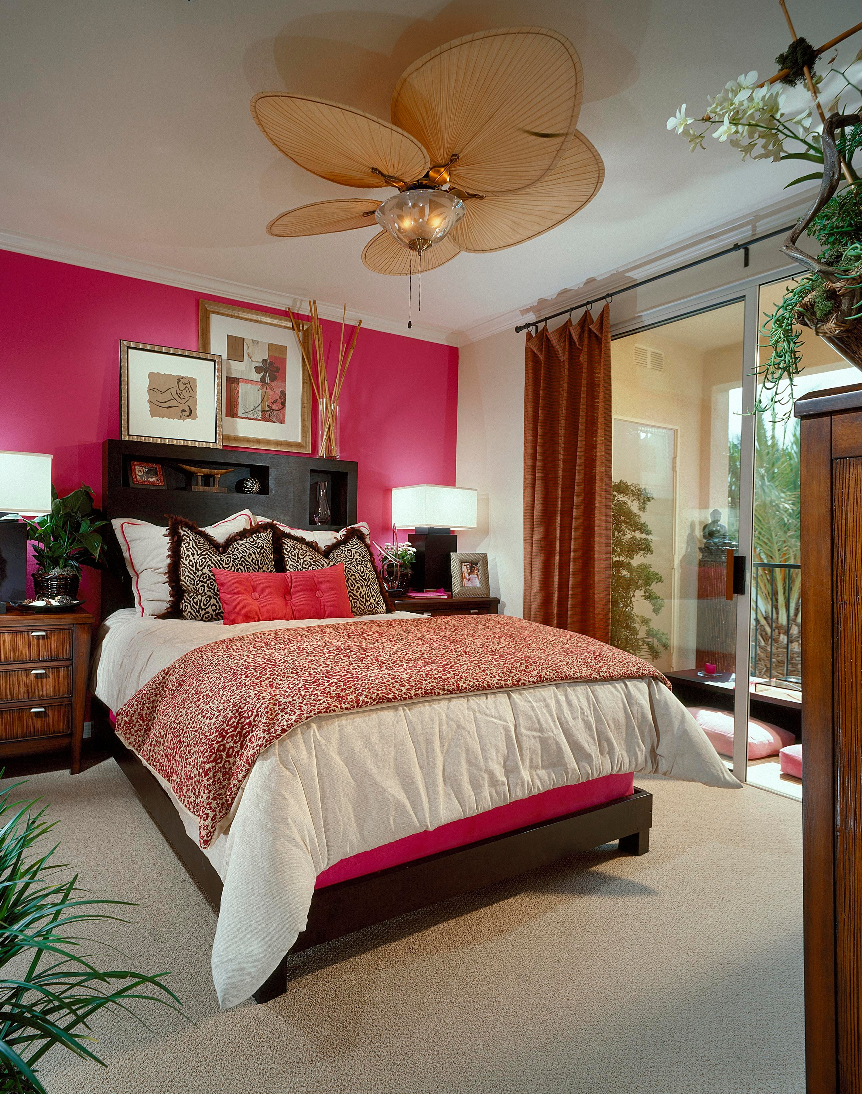 Magenta bedroom with dark wood furniture, patterned bedding, and a leaf-shaped ceiling light