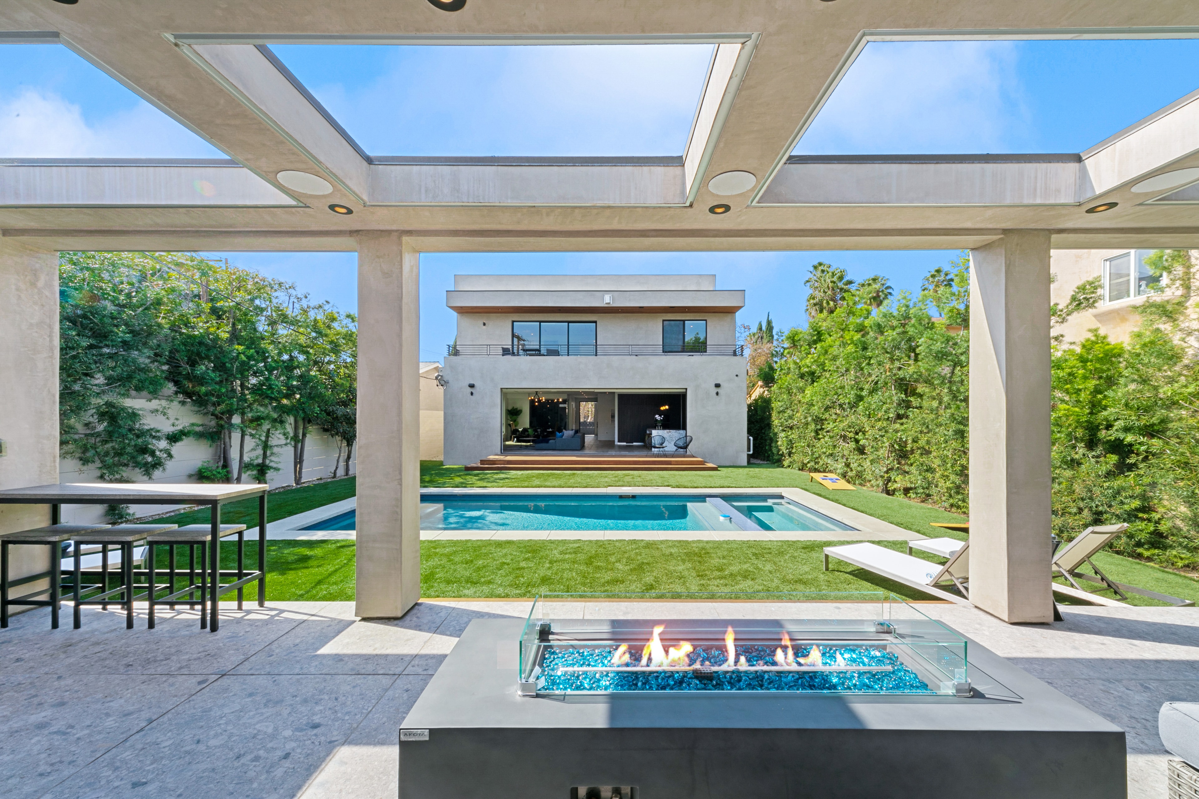 Outdoor fire table with pool and modern home beyond