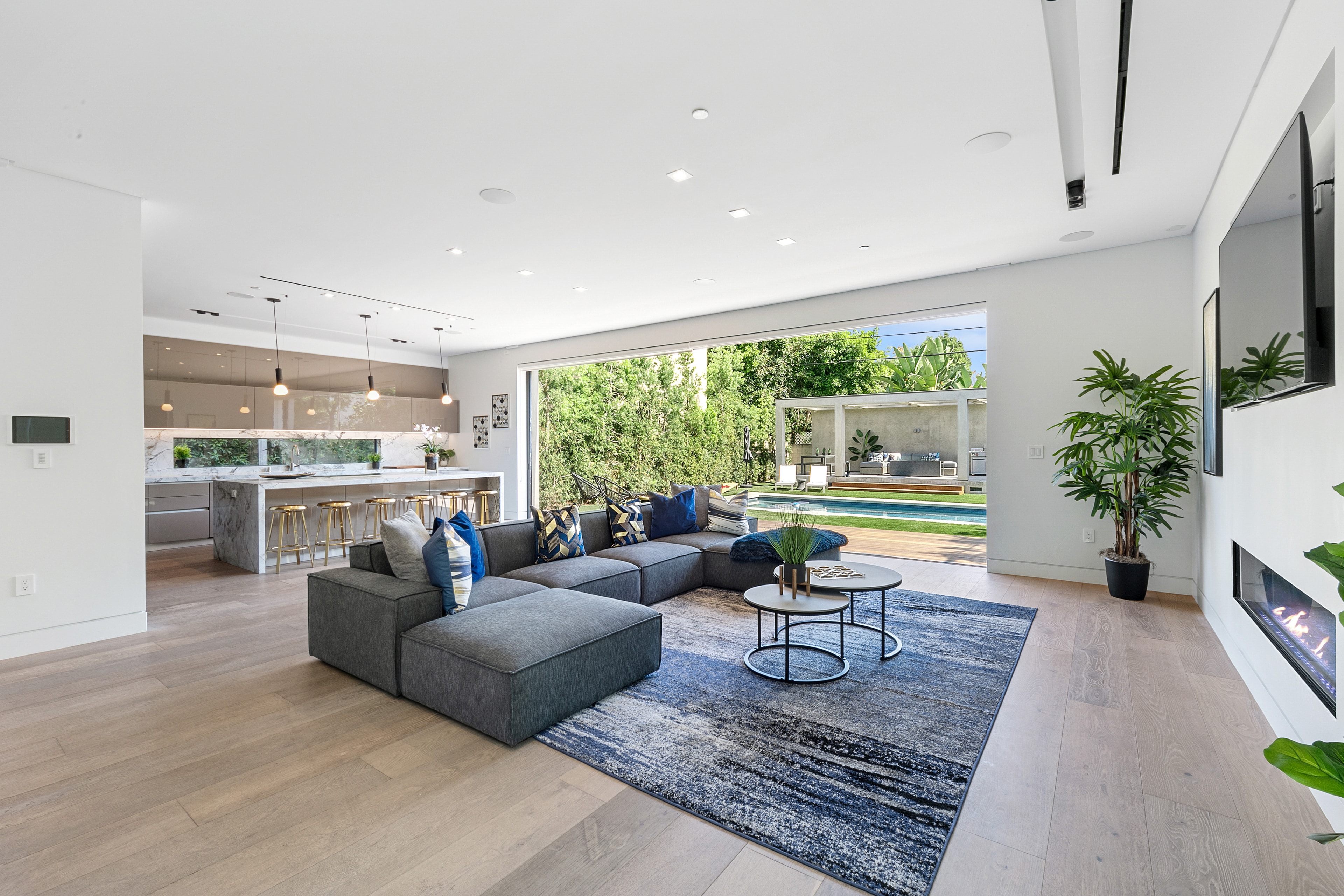 Contemporary living room with blue accents opening to the pool and outdoor pavilion