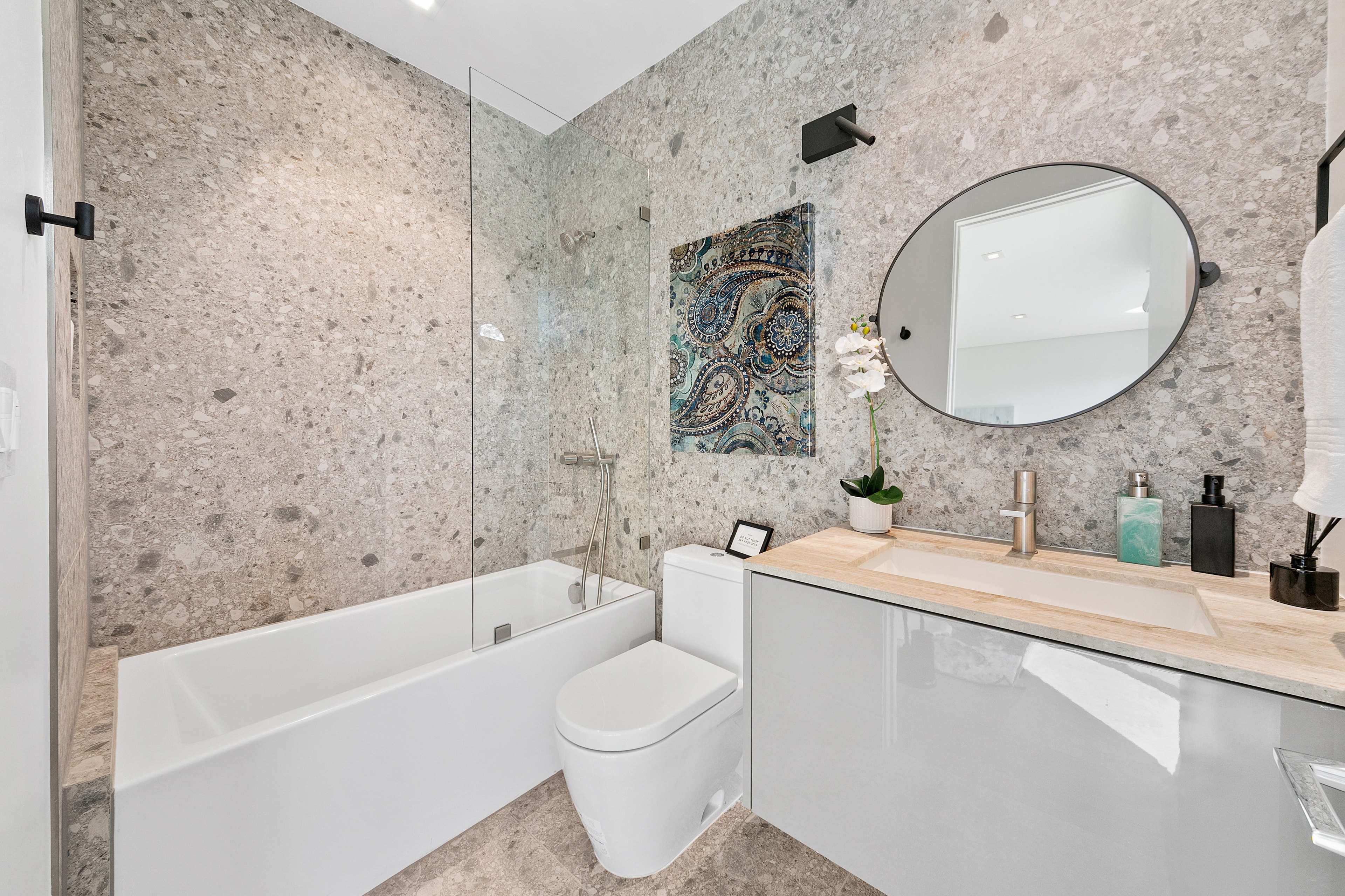 Terrazzo bathroom with bathtub, glass shower screen, and floating vanity