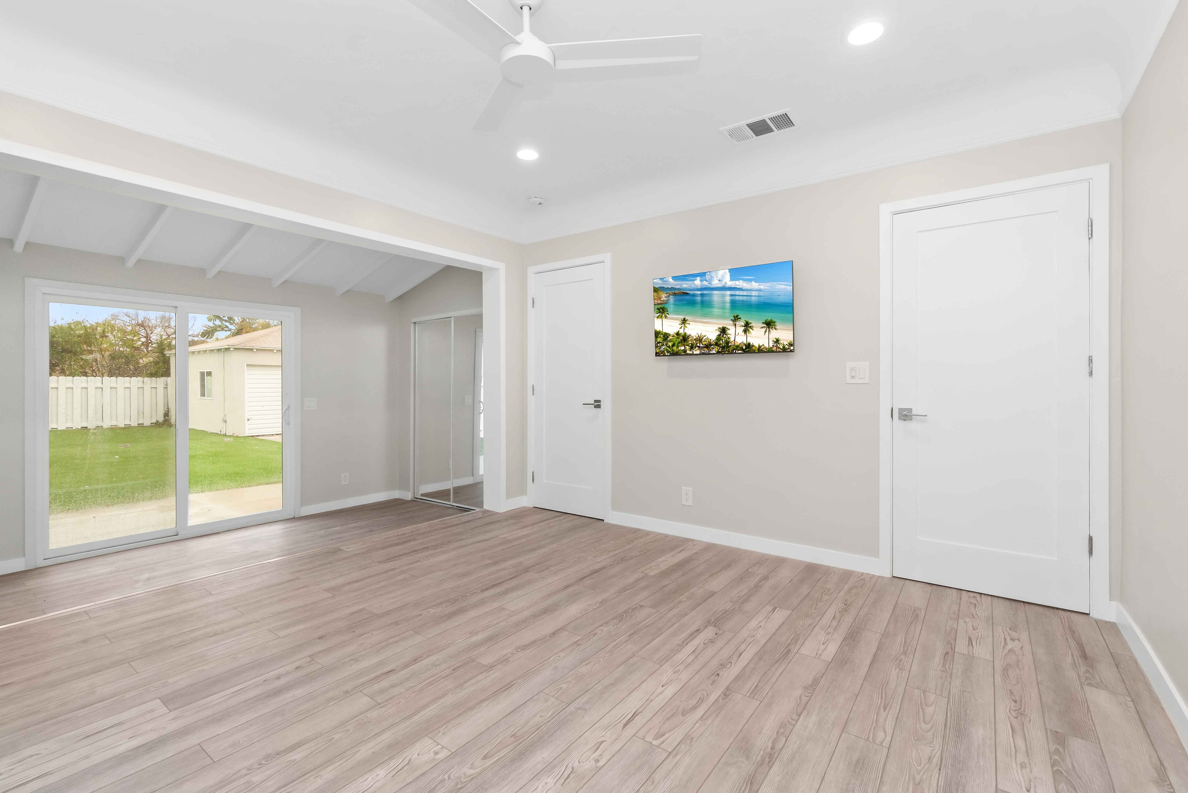 Remodeled family room with mirrored closet doors, raised floor detail, and beach artwork