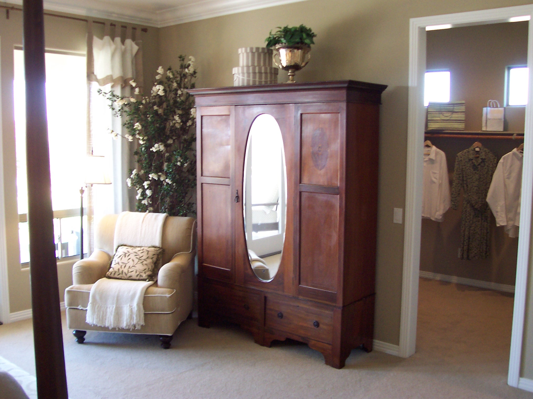 Bedroom dressing area with a wood armoire and upholstered chair