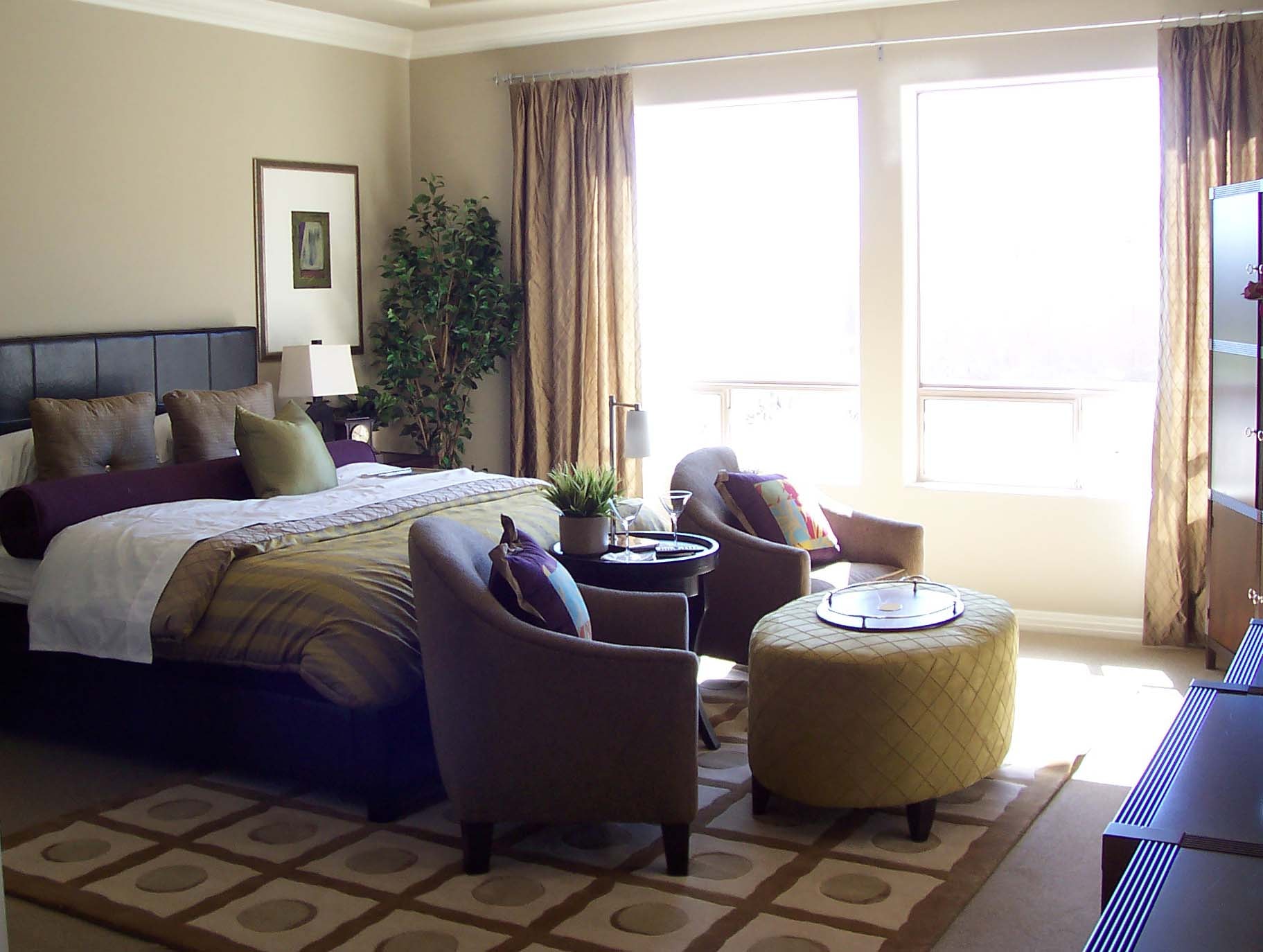 Primary suite with a sitting area, warm neutral textiles, and large windows